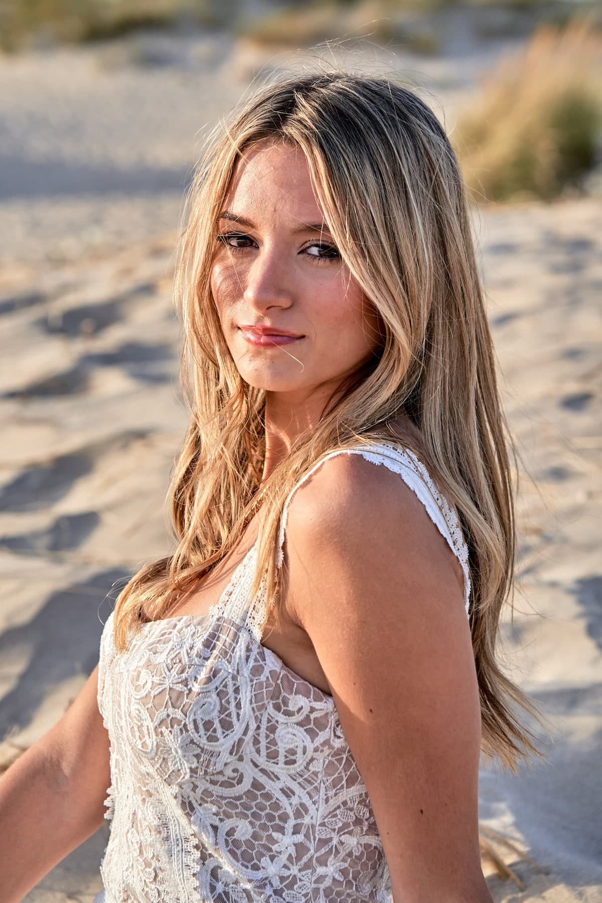 Young woman in a white lace dress on the dunes at Caparica