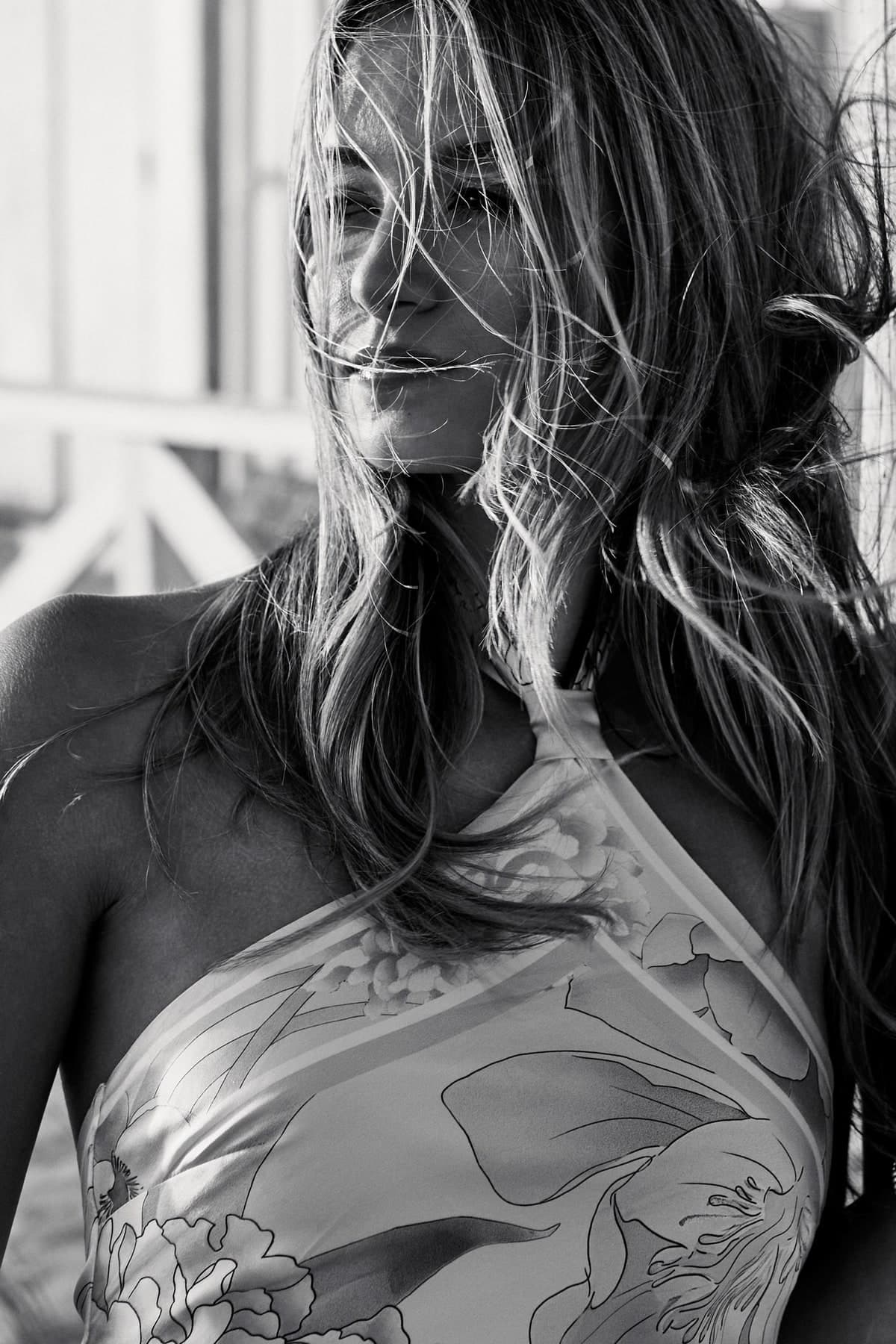 Black-and-white portrait with wind-blown hair by the beach huts