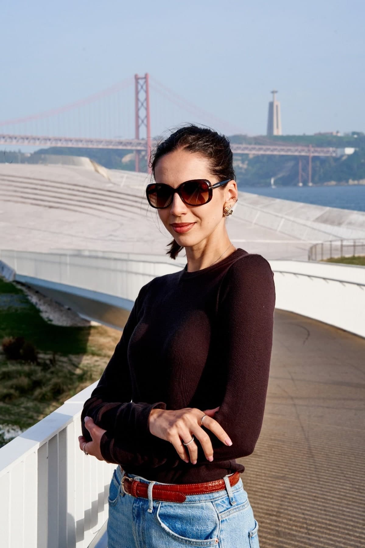 Woman in sunglasses on the riverside in Lisbon with the 25 de Abril bridge behind