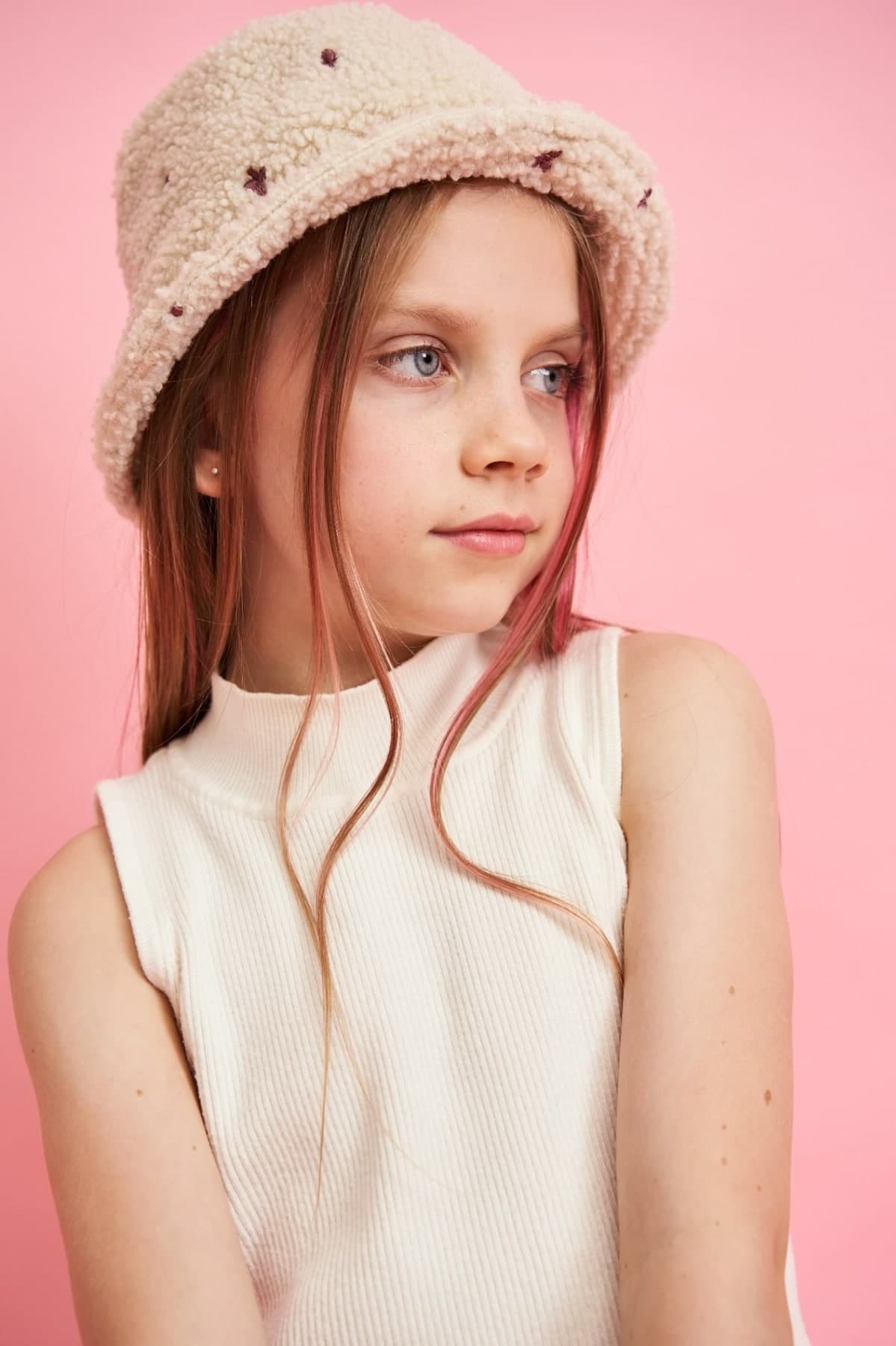 Studio portrait of a girl in a bucket hat against a pink background