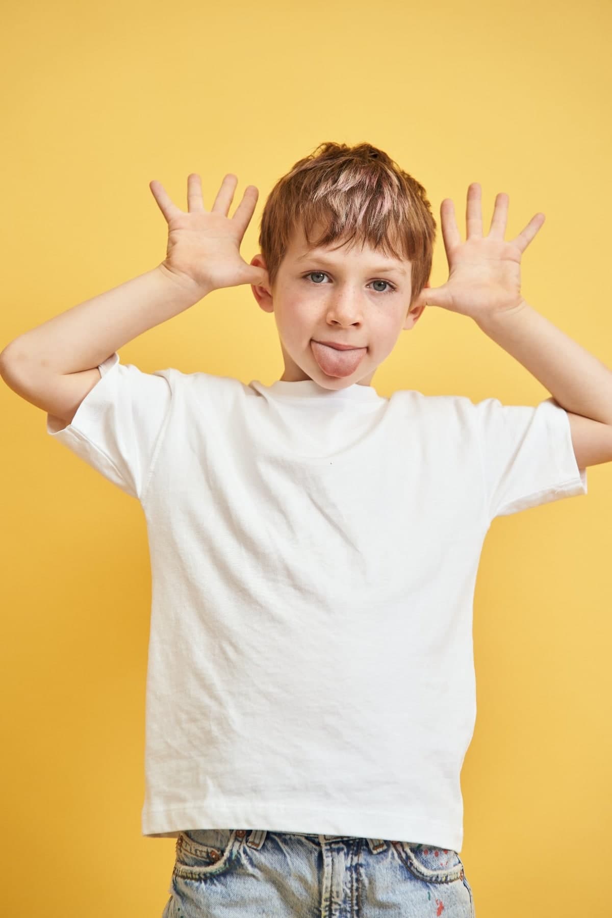 Studio portrait of a boy pulling a face against a yellow background